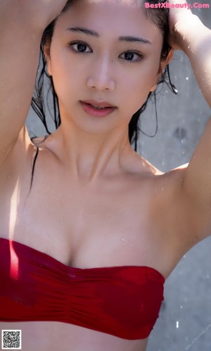 A woman in a white shirt and red bikini posing for a picture.