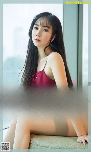 A woman in a red lingerie sitting on a bed.