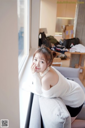 A woman sitting on a chair holding a cup of coffee.
