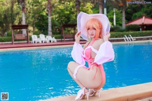 A woman in a pink bikini sitting by a swimming pool.