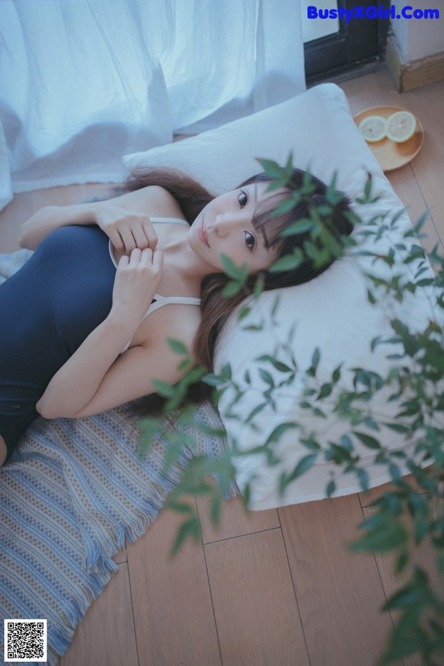 A woman laying on a bed next to a plant.