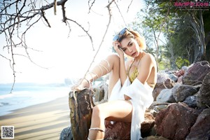 A woman in a bikini and hat on the beach.