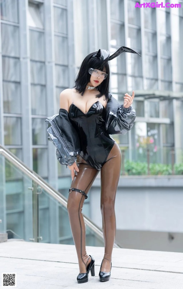 A woman in a black latex outfit posing for a picture.