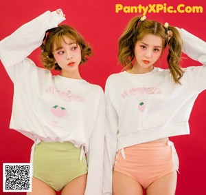 Two young women standing next to each other on a pink background.