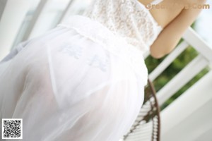 A woman in a white lingerie sitting on a chair.