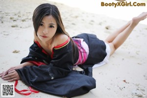 A woman in a black and pink dress sitting on the ground.