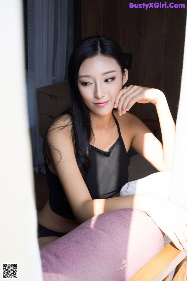 A woman sitting on top of a bed next to a window.