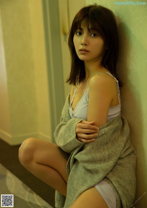 A woman in a white lingerie standing by a window.