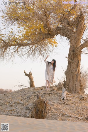 A woman sitting on top of a sandy beach.