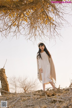 A woman in a white dress standing in the sand.