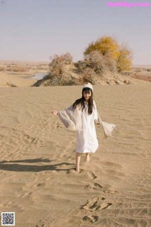 A woman sitting on top of a tree in the desert.
