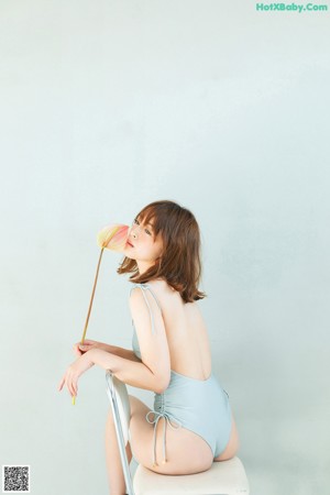 A woman sitting on a chair in a blue swimsuit.