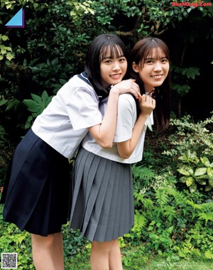 Two young women in school uniforms holding hands on a street.