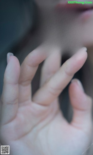 A close up of a woman's face with her hand on her chin.