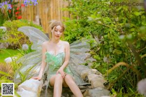 A woman sitting on top of a bed in a green dress.