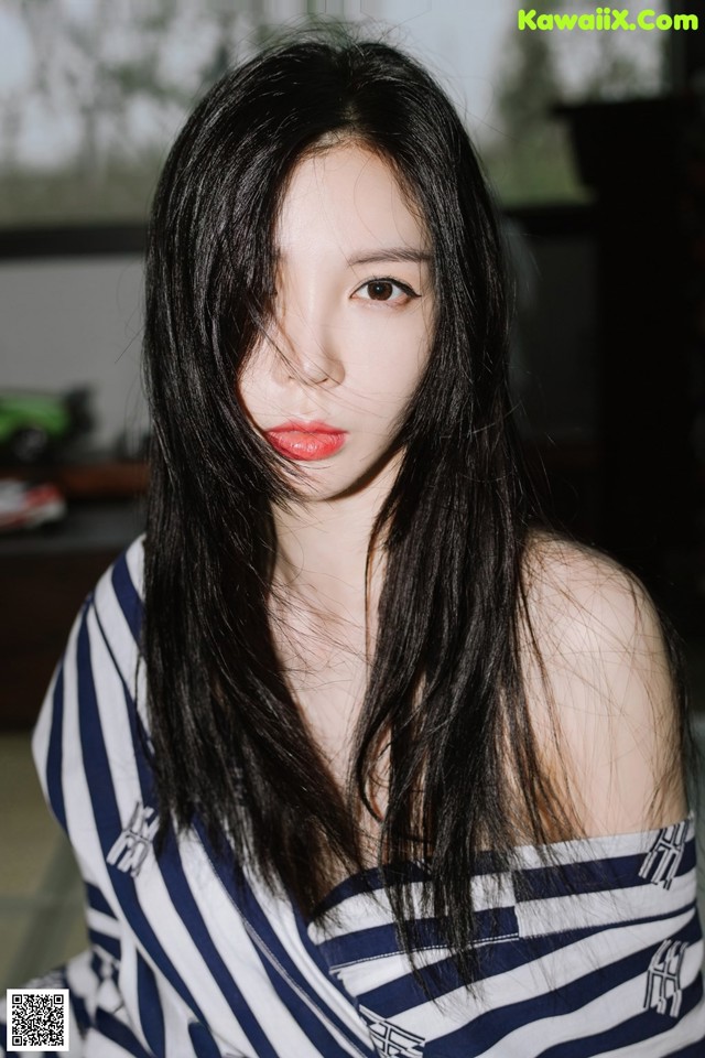 A woman with long black hair wearing a striped shirt.