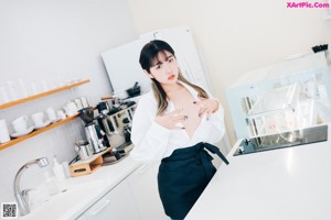 A woman in a white shirt and blue jeans posing in a kitchen.