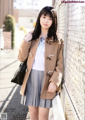 A woman wearing a black coat and a plaid scarf.