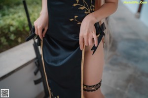 A woman in a black and gold outfit holding a gun.