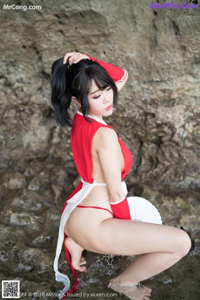 A woman in a red and white outfit is posing in the water.