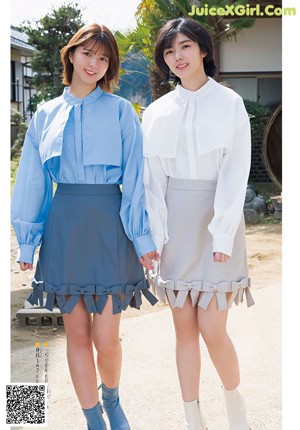 A couple of women standing next to each other on a sidewalk.