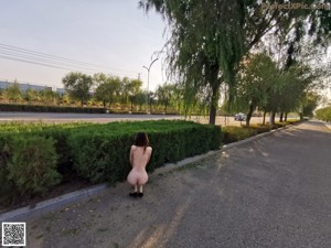 A woman walking down a dirt road next to a body of water.