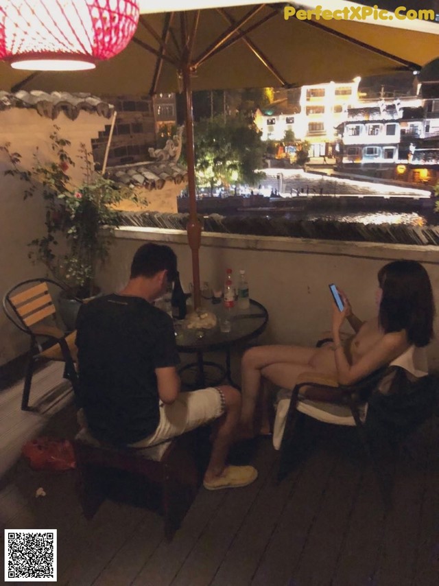 A man and a woman sitting at a table under an umbrella.