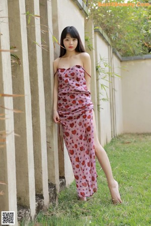 A woman in a pink dress sitting on a tree stump.
