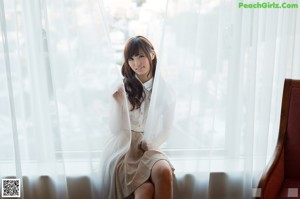 A woman in a white lingerie sitting on a bed.