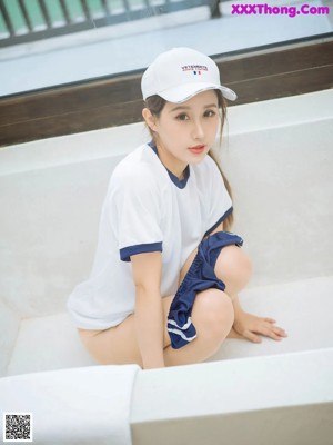 A woman in a white shirt and blue skirt is sitting on a bathtub.