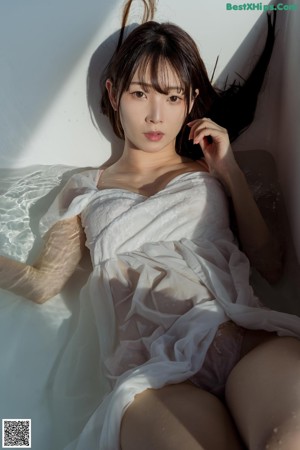 A woman in a white dress sitting in a bathtub.