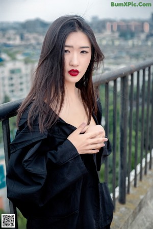 A woman in a black dress standing on a balcony.