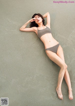 A woman in a bikini standing on a beach.