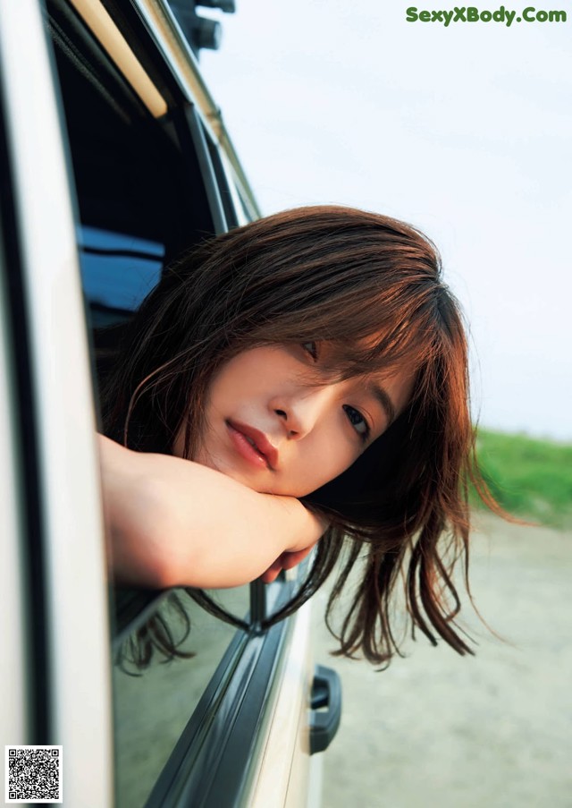 A young woman leaning out the window of a car.