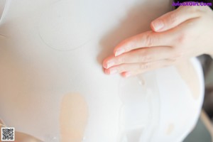 A woman in a white bodysuit and black stockings is putting on her panties.